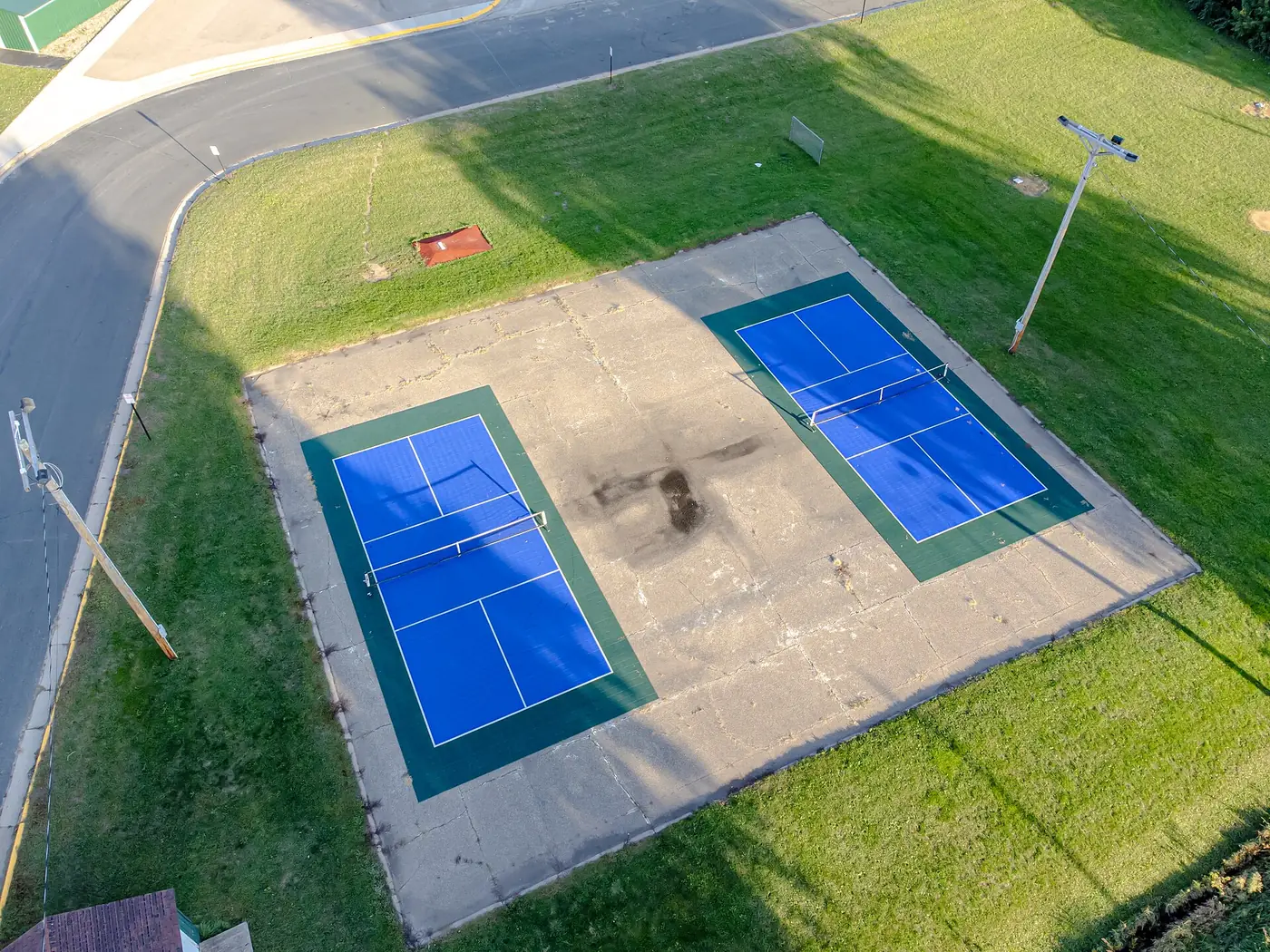 Two blue pickleball courts on a green pad