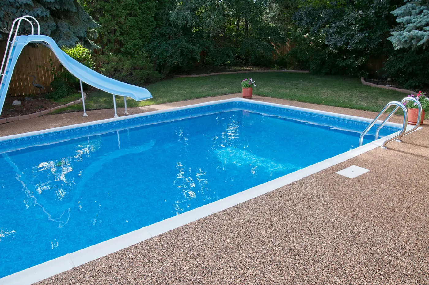 Rectangular backyard pool with a tan Rubber Stone deck